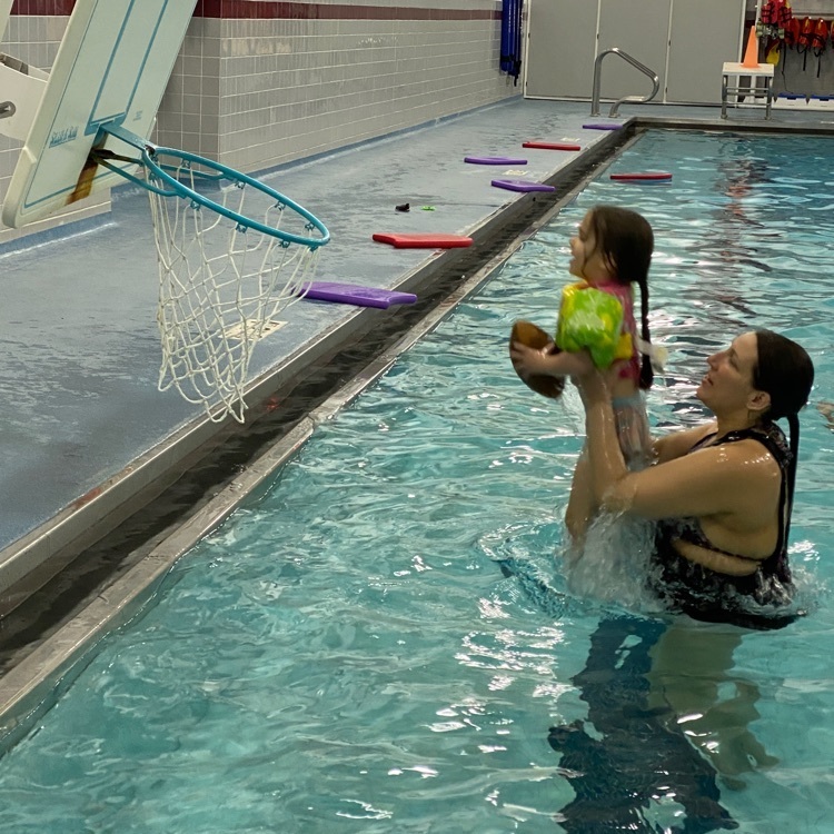mother and daughter playing basketball in the pool  